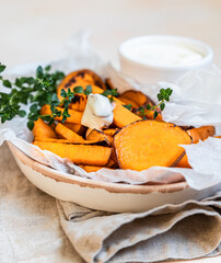 Healthy homemade baked sweet potato wedges with cream dip sauce and herbs. Healthy snack.