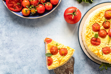 Piece of savoury tomato cheesecake with herbs decorated mint, blue background.