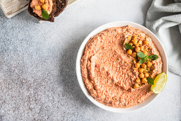 Roasted red pepper hummus garnish with mint and lime. Mashed chickpeas with red bell pepper, lime and mint. Vegetarian snack.