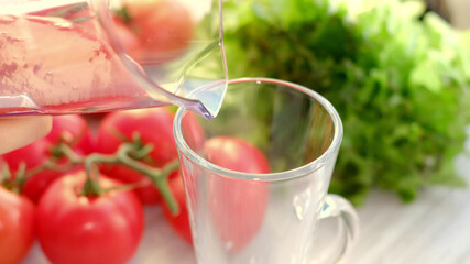 tomato juice with sprig of tomatoes on background. Tomato juice is poured into a glass.