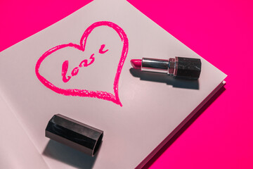 Heart painted with pink lipstick on a white sheet on a pink background. High quality photo