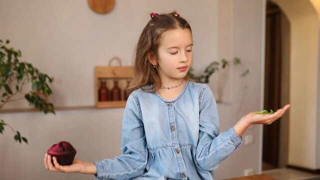 Little girl comparing food, choosing microgreen against sweet cake, Healthy dieting habit, concept of proper nutrition, the right choice food