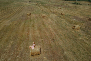 Hay. A woman lies in a field in the hay. Aerial view.