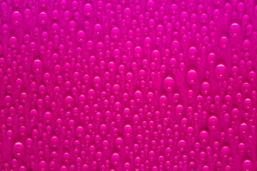 Drops of water on the glass on a purple background. Texture of a water drop as a background. Freshness after the rain. Wet clean nature ecology.