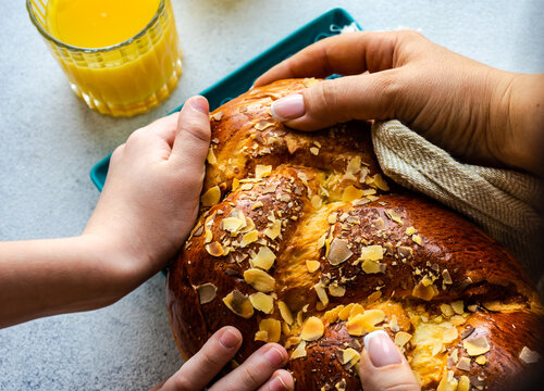 Mother and son sharing a traditional tsoureki Easter loaf with almonds next to a glass of orange juice