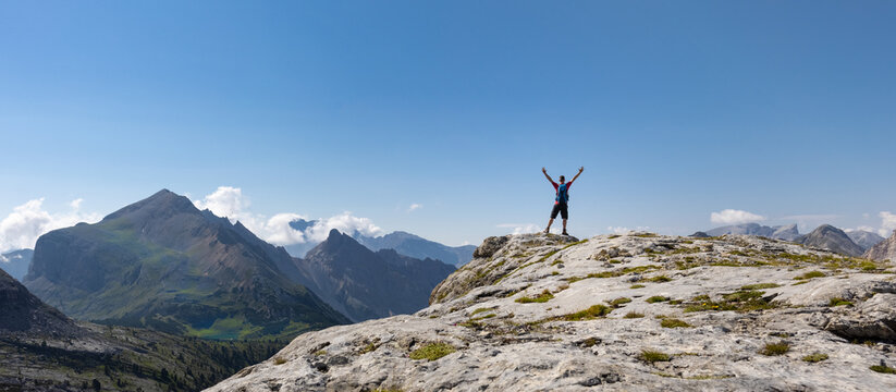 Hiker raising his arms in front of a panoramic mountain view