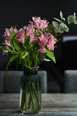 a bouquet of pink alstroemerias on a table in a dark interior