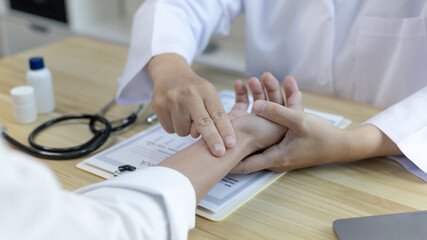 Medical professional measures the pulse of a male patient's wrist to check his heart rate in the...