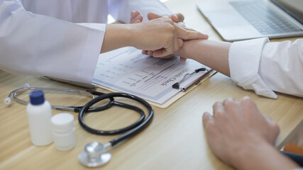 Medical professional measures the pulse of a male patient's wrist to check his heart rate in the...