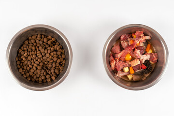 Two bowls with dog food, processed and natural stuff. Comparing of different kind of diet. The process of changing from one system to another. White background, copy space.