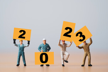 Miniature worker showing 2023 on yellow board for preparation merry Christmas and happy new year...
