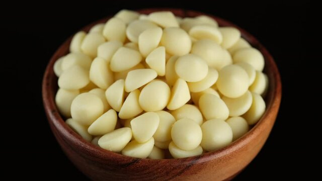 White chocolate chips in wooden bowl, rotation. Confectionery concept. 4K UHD video