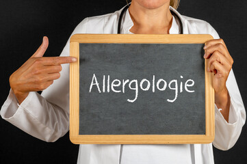 Ärztin mit einer Tafel auf der Allergologie steht
