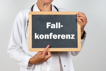 Ärztin mit einer Tafel auf der Fallkonferenz steht