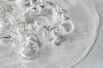 Transparent facial serum with bubbles on light grey background macro. Liquid bubbly gel with...