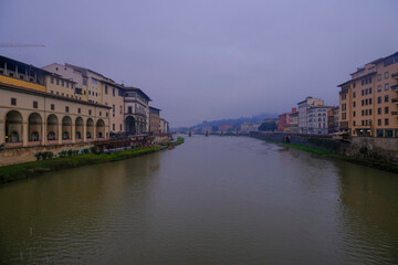 Obraz premium Florence, Italy: View from the Florence Ponte Vecchio on a rainy day on River Arno, canal, and colorful buildings on the banksides