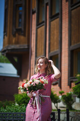 Young happy blonde woman in a pink dress with a large bouquet of flowers walks around the old European city and enjoys life on a summer day, beautiful portraits with a huge bouquet of flowers.