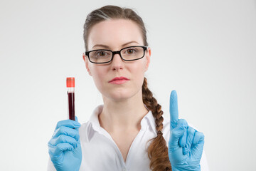 Female doctor or scientist holding a blood probe and is rising a finger for attention