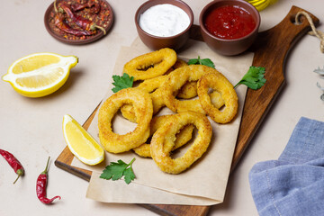 Fried squid rings with two sauces, lemon and herbs. Fast food. Appetizer.