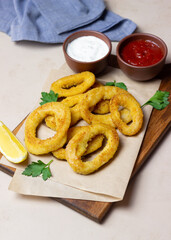 Fried squid rings with two sauces, lemon and herbs. Fast food. Appetizer.