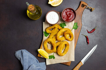 Fried squid rings with two sauces, lemon and herbs. Fast food. Appetizer.