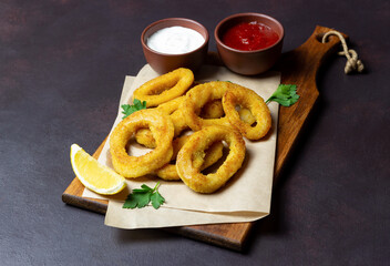 Fried squid rings with two sauces, lemon and herbs. Fast food. Appetizer.