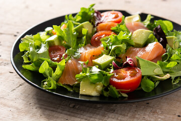 Salmon and avocado salad in plate on wooden table