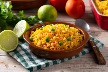 Traditional Mexican rice served with green peas in bowl on wooden table