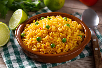 Traditional Mexican rice served with green peas in bowl on wooden table