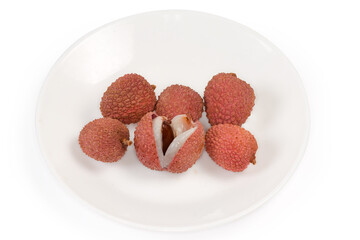 Whole and one halved ripe lychee fruits on white dish