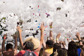 Foam party entertainment, people have fun raising hands catch soap bubbles, summer entertainment festival in aquapark, background or texture of white foam with copy space