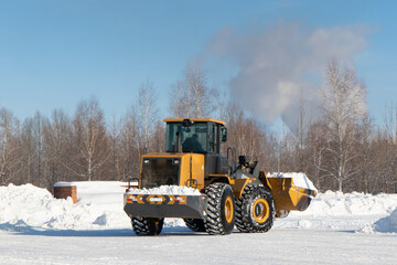 Big yellow tractor cleaning snow parking