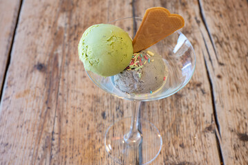 Pistachio and almond ice cream served in a glass with sprinkles and a wafer