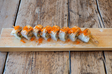 Prawns sushi rolls with nori seaweed and rice served on a wooden platter
