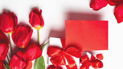 Bouquet of red tulips, envelope, gift box, on a white background. Valentine's Day greeting card. Copy space. Top view.