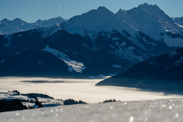 beautiful view of a foggy valley and of the alps in the morning at a sunny winter day on the mountains