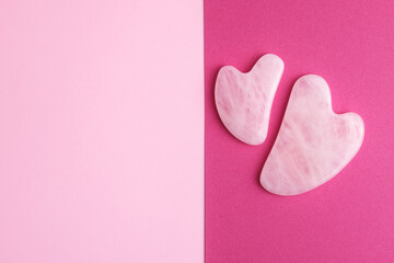 Fototapeta premium Rose quartz face massage stones on two color pink and crimson background with empty space for your design. 