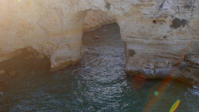 Stone arch in sea water. Sunlight makes a highlight. Natural roughness. Good fishing spot.