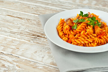 Pasta with meat in a white plate. Pasta on a shabby wooden table. Copy space and free space for text near food.