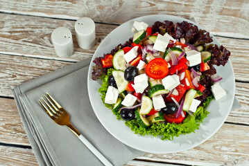 Greek salad on a white background. Salad in a plate on an old wooden table.