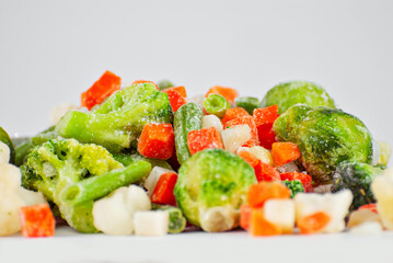 A mixture of frozen vegetables in a pile. Preparation for a dish on a white background.