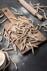 Whole grain wheat apulian pasta called Pizzarieddi or maccaruni on a cutting board on black table....