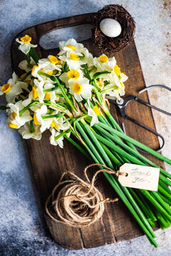 Overhead View Of A Bunch Of Narcissus Flowers On A Chopping Board With A Thank You Tag, String And Scissors