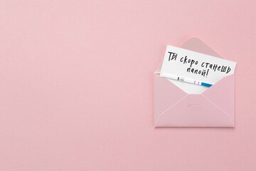 positive pregnancy test in pink envelope on pink background, postcard with the inscription you will be a dad in russian, pregnancy concept.