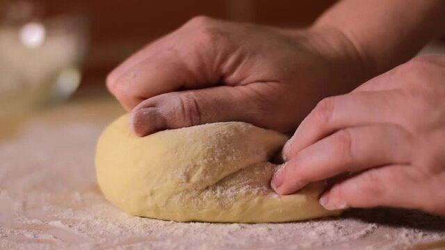 Baker is kneading and folding yeast dough on the board with flour. Baking at home
