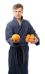 portrait of a man in a gray terry bathrobe. Satisfied, happy man holds fruits, oranges. better at home, stay home. vitamins protect you from disease. isolated.