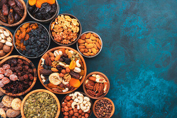 Nuts and dried fruits in assortment. Dry apricots, figs, raisins, walnuts, almonds and other. Blue table background, top view, copy space