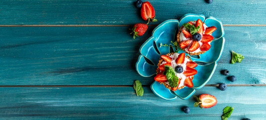 Breakfast toasts crostini appetizers with brie cheese, strawberries and mint. Close up on a serving board catering. Party food concept