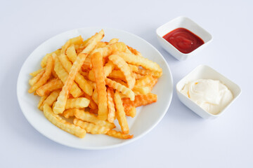 Plate of fries with mayonnaise and ketchup on white table. 