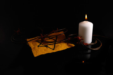 Holocaust memory day. Arbed wire and burning candle on black background